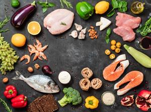Healthy foods including fish, chicken, and vegetables shown on a black table