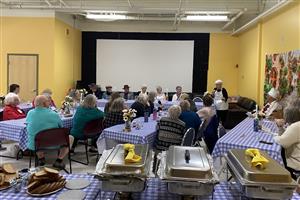 Seniors are shown eating a meal provided by Age Well at the R.E.C Zone