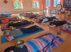 People lay down on yoga mats during a sound bath, where the instructor creates sounds using different instruments to calm the body and mind.