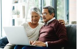 An older couple looks at a laptop while watching a seminar.