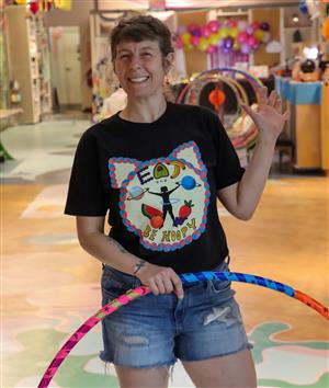 A woman holds a hula hoop near her head and smiles