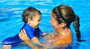 A parent and their child swim together during swim lessons.