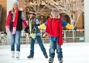 A family is shown skating on an ice rink together, holding hands and smiling