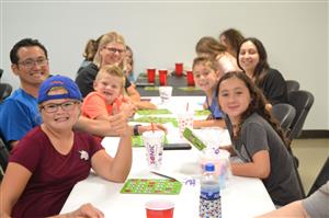 A family is shown smiling and laughing while playing bingo together