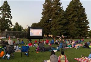 A movie is shown on a screen outside at the park
