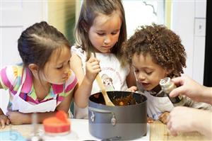 Children work together to cook dinner in a pot on the stove