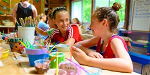 Campers smile to each other as they work on an art project