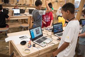 Campers work on coding on their laptops
