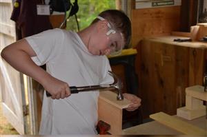 A camper uses a hammer while in woodworking