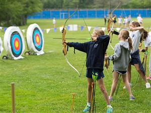 2 Girls shooting on an Archery Range & 1 girl watching