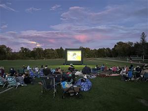 Families and friends watch a movie in the park together at Village Community Park in 2026