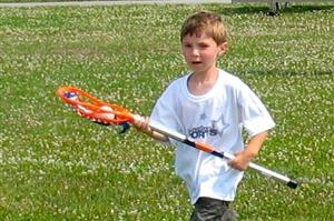 Boy with lacrosse stick carrying a ball