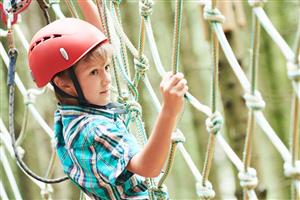 Boy in climbing gear moving across a rope net